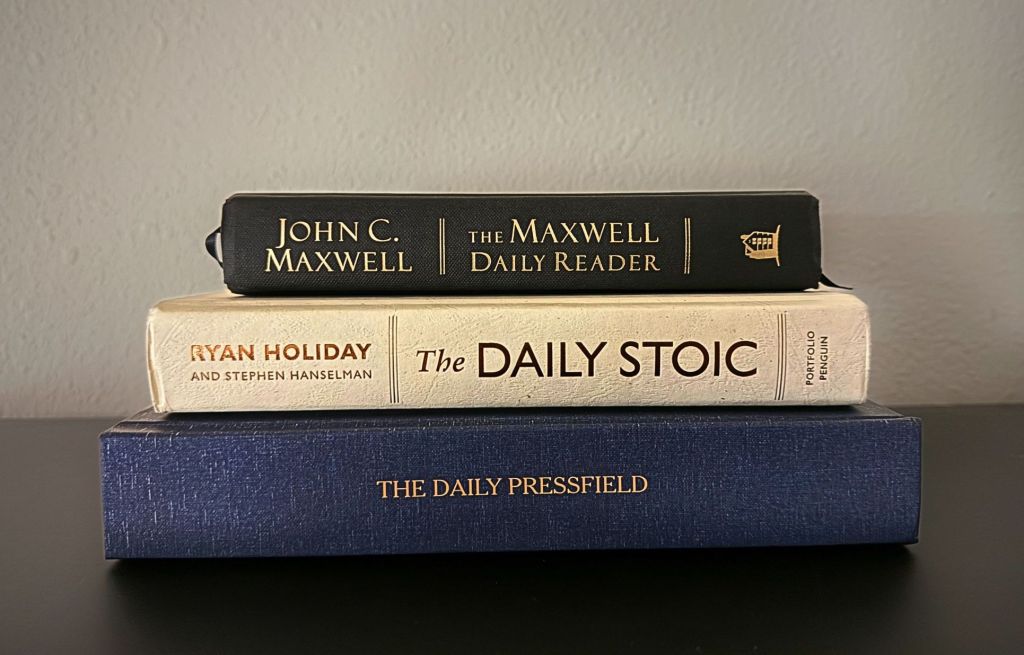 Stack of books: Maxwell Daily Reader, Daily Stoic, Daily Pressfield